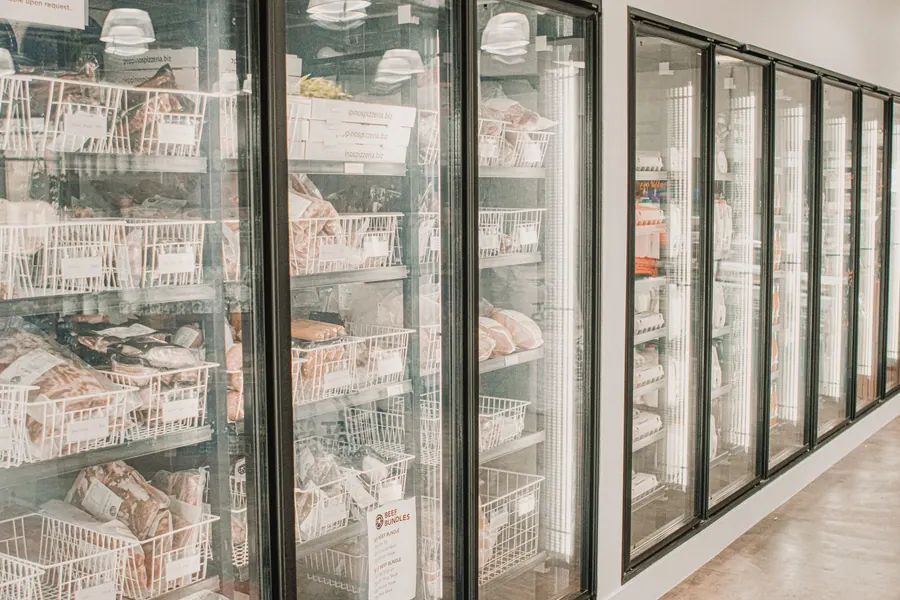 Produtos congelados em balcão frigorífico com portas de vidro